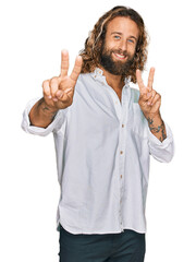 Handsome man with beard and long hair wearing casual clothes smiling looking to the camera showing...