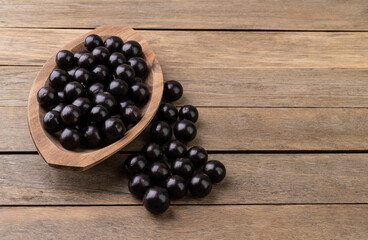 Jabuticabas on a bowl over wooden table with copy space