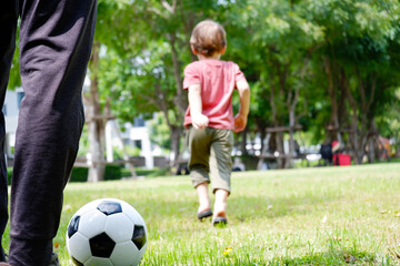 A boy runs and kicks football in the grass.