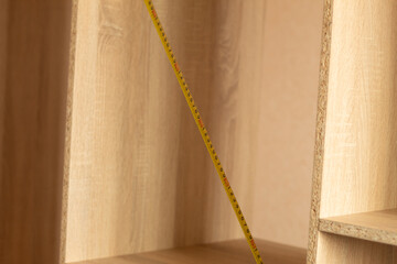 Measuring a wooden product with a tape measure. Photo without a person. Measure the diagonal of...