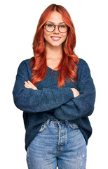 Young redhead woman wearing casual sweater and glasses happy face smiling with crossed arms looking...