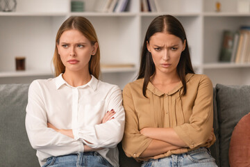 Two ladies angry after conflict sitting on sofa at home