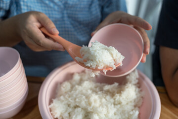 Steamed boiled jasmine rice scooping up by plastic spoon. Woman use rice spoon to scoop rice from...