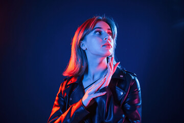 Against dark blue background. Cool young woman portrait in neon colors