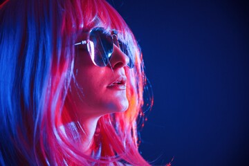 White hair of medium length. Woman is in studio with neon colors