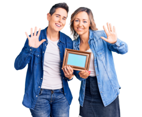 Couple of women holding empty frame waiving saying hello happy and smiling, friendly welcome gesture