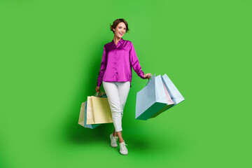 Full length photo of cheerful adorable girl shopaholic wearing nice clothes carrying bags isolated...