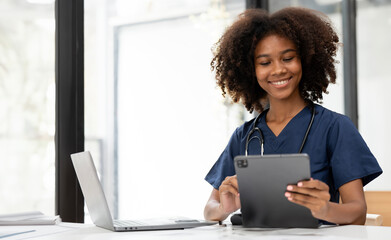 Happy african nurse student working on digital tablet and laptop in office room.