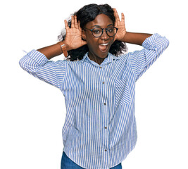Beautiful african young woman wearing casual clothes and glasses smiling cheerful playing peek a boo with hands showing face. surprised and exited