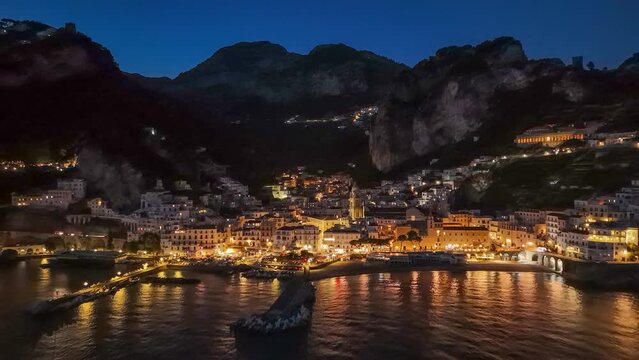 Aerial evening shot of Amalfi town with city lights. Famous Amalfi coast in Campagna, Italy. 4K, UHD