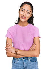 Hispanic teenager girl with dental braces wearing casual clothes happy face smiling with crossed...
