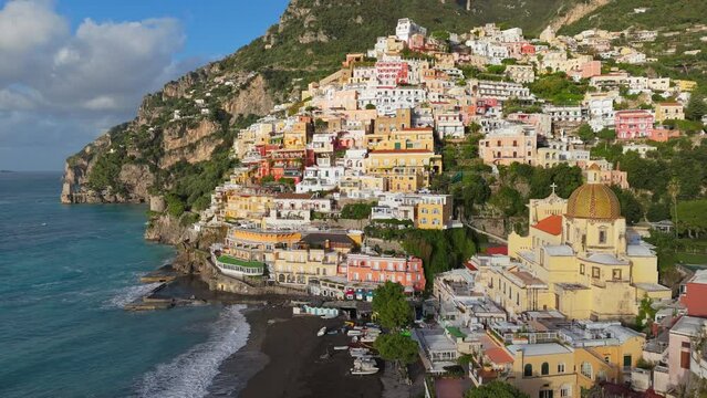 Famous tourist resort of the Amalfi coast - Positano. Flying above colorful houses, church and beach with turquoise water - Positano village, Italy. UHD, 4K