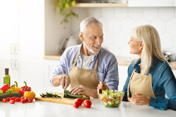 Portrait of happy senior couple cooking food in kitchen at home