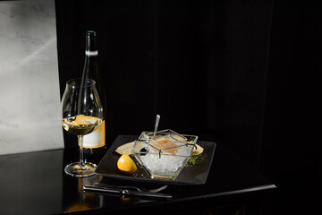 Fototapeta na wymiar Pike fish caviar, on ice, with croutons, lemon, on a transparent dish, on a dark background