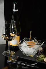 Pike fish caviar, on ice, with croutons, lemon, on a transparent dish, on a dark background