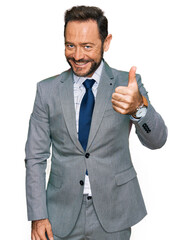 Middle age man wearing business clothes doing happy thumbs up gesture with hand. approving expression looking at the camera showing success.