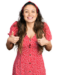 Young hispanic girl wearing casual clothes success sign doing positive gesture with hand, thumbs up smiling and happy. cheerful expression and winner gesture.