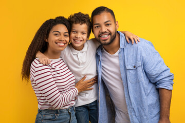 Happy Black Family Of Three With Son Embracing And Smiling At Camera