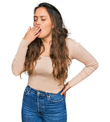 Young hispanic girl wearing casual clothes bored yawning tired covering mouth with hand. restless...