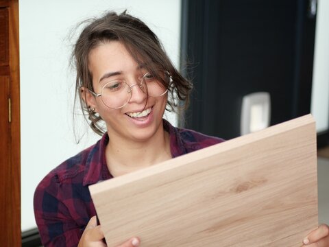Femme souriante tenant dans ses mains une planche de bois pour faire du bricolage