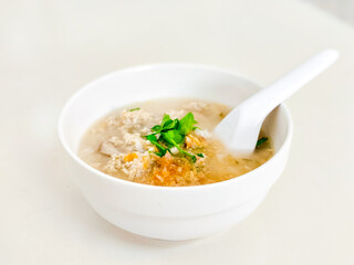 Hot chicken boiled rice soup in a white ceramic bowl. Delicious Chinese food.