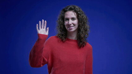 Cheerful Woman in Red Sweater Greeting with Hand Wave, Blue Background
