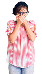 Beautiful young woman with short hair wearing casual clothes and glasses shocked covering mouth with hands for mistake. secret concept.