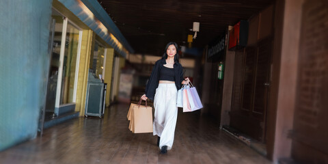 Fototapeta premium Happy beautiful young stylish woman asian with shopping bag while walking in the mall on holiday Black Friday
