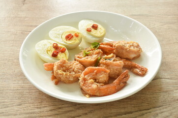 deep fried shrimp garlic and pepper with slice boiled egg  dressing chop chili in fish sauce on plate 