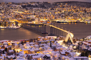 Panorama of Norwegian city of Tromso in the winter. Snowy roofs, bridge, embankment near the port...