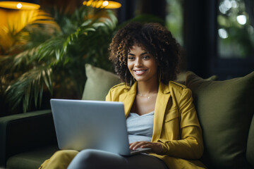 Fototapeta premium Portrait of a smiling African American female freelancer working on a laptop.