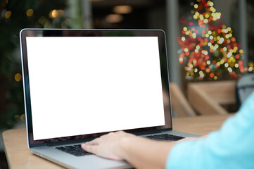 Blank white desktop screen and women are use laptop at home that has christmas tree decorated with christmas lights.