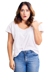 Fototapeta premium Young beautiful caucasian woman wearing casual white tshirt surprised pointing with hand finger to the side, open mouth amazed expression.