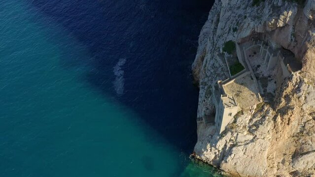 Aerial drone top view of Porto Flavia mines entrance on the rocks in Sardinia, Italy