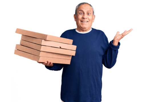Senior handsome man holding pizza boxes celebrating victory with happy smile and winner expression with raised hands