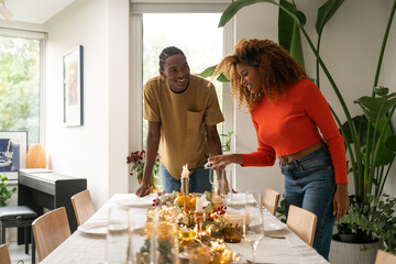 Smiling multiracial woman looking at table and lighting candles