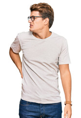 Handsome caucasian man wearing casual clothes and glasses suffering of backache, touching back with hand, muscular pain