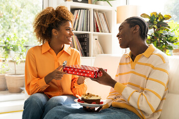Loving boyfriend congratulating girlfriend, excited curious woman holding gift box