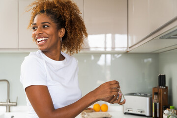 Positive african american woman standing at the kitchen and cooking