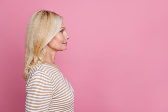 Side profile photo of satisfied person with blond hair dressed striped t-shirt look at logo empty space isolated on pink color background