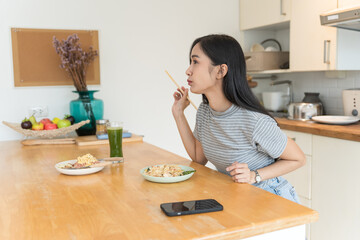 Asian Girl  eating Thai food in kitchen counter Home delivery food feeling happy 