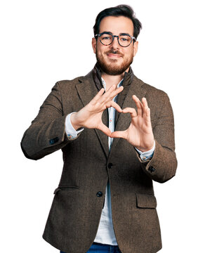 Young hispanic man wearing business jacket and glasses smiling in love doing heart symbol shape with hands. romantic concept.
