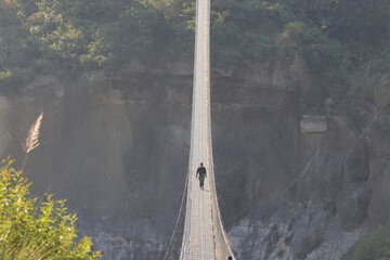 the local villager bearing the straws and walk on one of the long pedestrian suspension bridge in...
