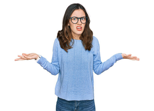 Young beautiful woman wearing casual clothes and glasses clueless and confused with open arms, no idea concept.