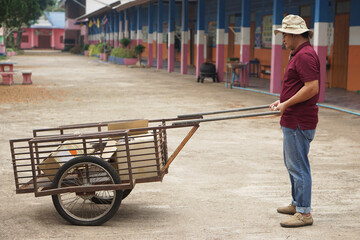 Asian man janitor is carrying wheel cart to keep garbage in school. Concept, service occupation....
