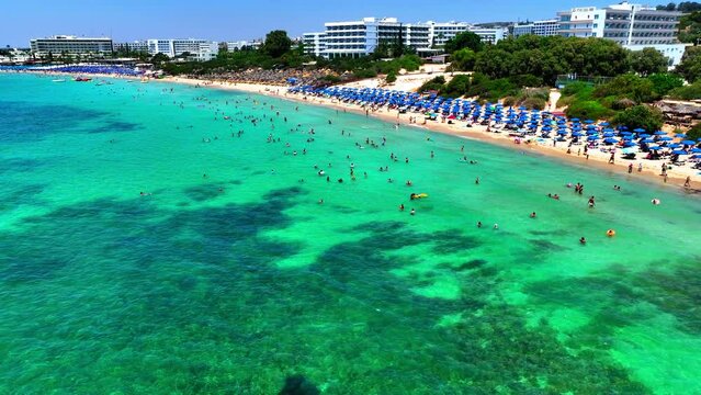 Aerial Forward Shot Of People Enjoying In Sea At Beach During Vacation By Hotel Buildings In City Against Clear Sky - Famagusta, Cyprus