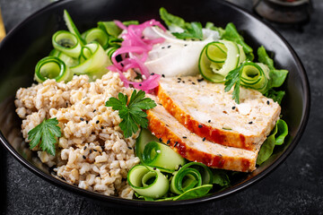 Brunch or lunch. Plate with oatmeal, chicken meatloaf, cucumber and green herbs. Health food.