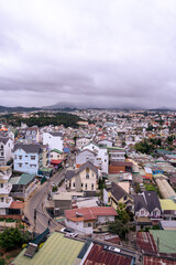 Fototapeta premium View on roofs in the city of Dalat. Da Lat and the surrounding area is a popular tourist destination of Asia. City with fogs and mountains