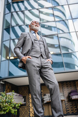 Portrait of senior man with beard businessman in suit stand outdoor