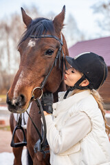 Obraz premium Beautiful blond professional female jockey kissing brown horse on farm. Friendship with horse